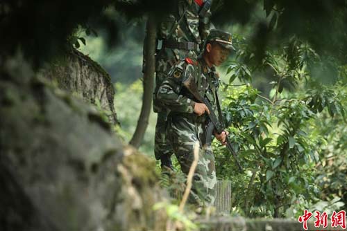 　圖為武警官兵提著槍支搜尋犯罪嫌疑人蹤跡。